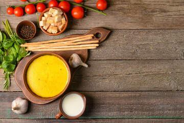 Bowl with tasty garlic cream soup on wooden background