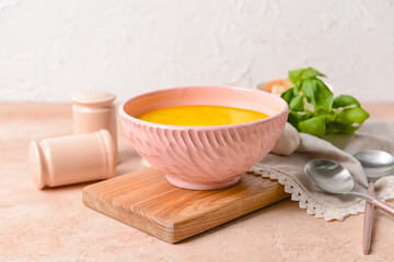 Bowl with tasty garlic cream soup on color background