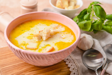 Bowl with tasty garlic cream soup on color background