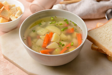 Bowl with tasty garlic soup on color background