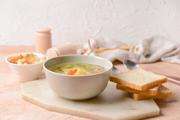 Bowl with tasty garlic soup on color background