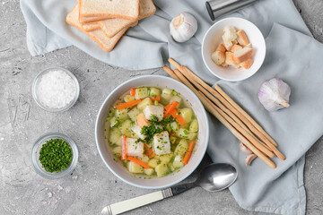 Bowl with tasty garlic soup on grey background