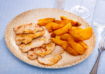 Fried barbecue pork meat with baked potato on a plate in a pub