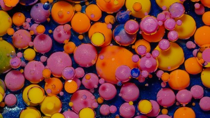 Bright ink bubbles mixed with liquid substance of oil, milk, soap. Floating acrylic paint on colorful surface. Abstract multicolor macro hypnotic transformation themes or wallpaper painting background