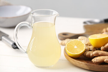 Glass jug of healthy ginger juice on table