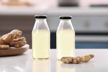 Bottles of healthy ginger juice on table in kitchen