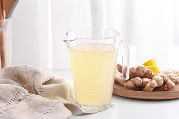 Jug of healthy ginger juice on table in kitchen