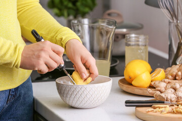 Woman grating ginger at table in kitchen