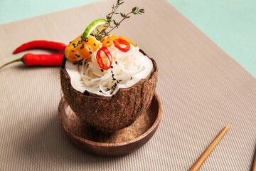Bowl with Thai noodle soup on color background
