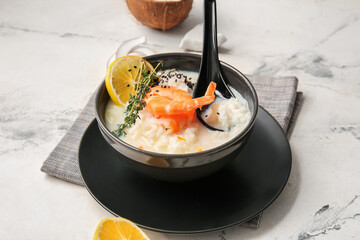 Bowl with Thai rice soup on light background
