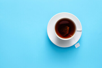 Cup of hot aromatic black tea on color background