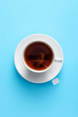 Cup of hot aromatic black tea on color background