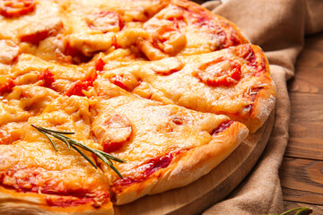 Board with tasty pizza on wooden background, closeup