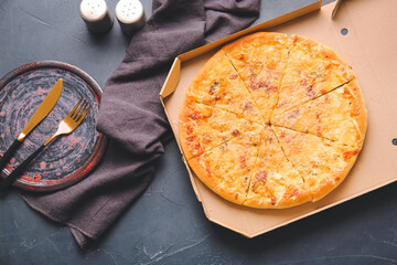 Cardboard box with tasty pizza on dark background