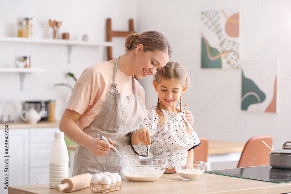 Poster happy woman and her little daughter cooking in kitchen