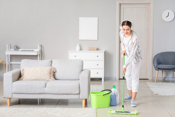 Obraz premium Young woman mopping floor in room