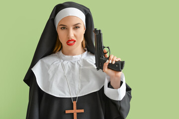 Sexy nun with gun on color background