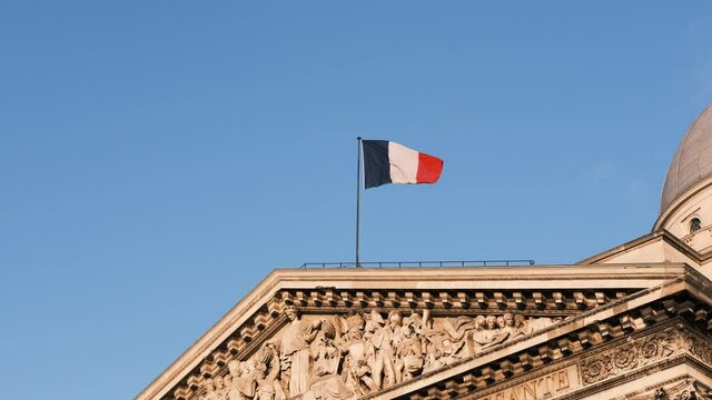 French flag waving in the air on the Pantheon in Paris blue sky sunny day