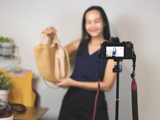 woman  working at home,  using camera phone to live or record video selling her woven bag. Indoor,  selective focus. Business and online selling concept.