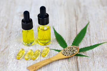Cannabis seeds in a wooden spoon are placed on top of the cannabis leaves. Oil extracted in a glass bottle. The idea of extracting hemp oil is a natural drug. The idea of planting seeds is seedlings.
