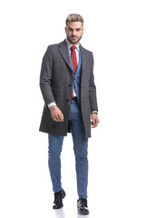 attractive young man in long coat smiling and posing