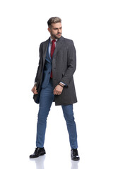 cool elegant fashion model in long coat looking to side and posing