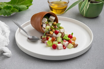 fresh green salad served on a white plate with beans, legumes, and pomegranate seeds