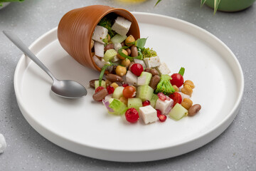 fresh green salad served on a white plate with beans, legumes, and pomegranate seeds