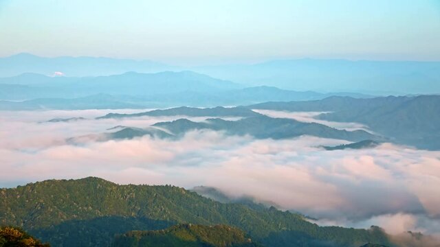 Time-lapse of the sea of clouds with fog flowing on the top of green mountains