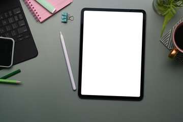 Top view of mock up digital tablet with white screen, smart phone, stylus pen and notebook on gray background.