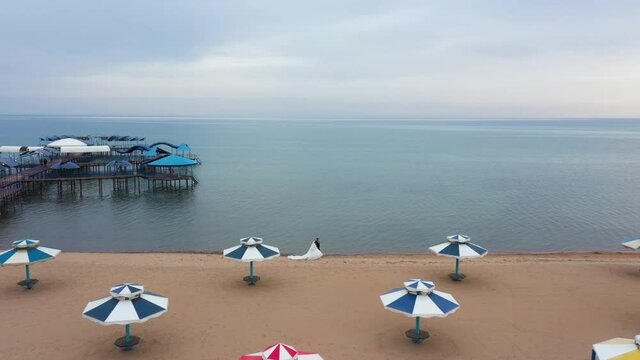 Newlyweds are walking along the shore. Bird's-eye view.