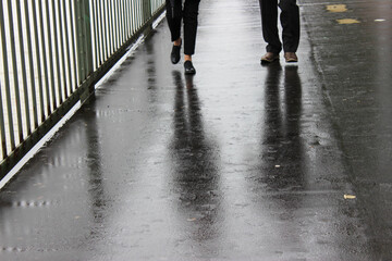 Silhouette of two people walking on wet ground
