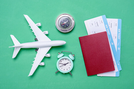 Plane, airline tickets and passport on a green background with a top view. Concept of travel and buying air tickets