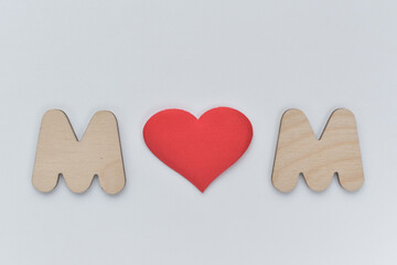 Two wooden letters M and a red heart between them. Concept of love for mom, love of two men.