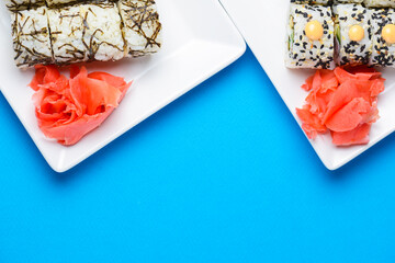 Sushi large set served on a white plate over blue background. Traditional Asian Japanese cuisine concept.