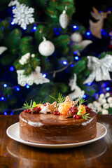 Christmas chocolate cake decorated with pomegranate seeds and tangerine. Cake for New Year celebration.