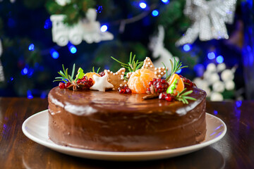 Christmas chocolate cake decorated with pomegranate seeds and tangerine. Cake for New Year celebration.