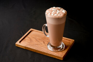 Hot chocolate with marshmallows isolated on black background. Glass of cocoa over black.