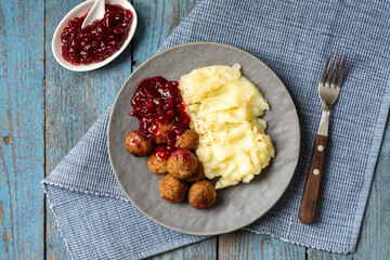 Swedish meatballs with mashed potatoes and lingonberry jam top view. A traditional Scandinavian dish in a ceramic plate on a wooden table