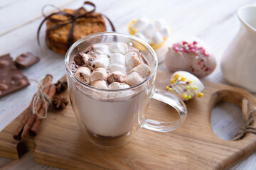 A mug of marshmallow drink on the table by the window.