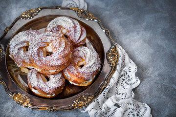 custard cake rings with cream and powdered sugar on a metal platter