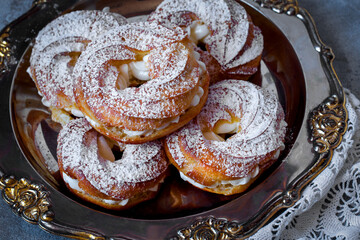custard cake rings with cream and powdered sugar on a metal platter