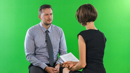 Female presenter interviewing man in tv studio, green screen concept