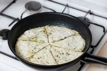 Flatbread with onion cheese and beacon fried in a pan.