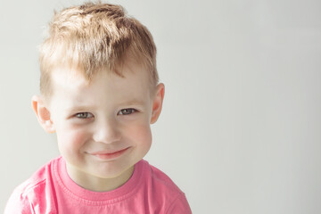 Fototapeta premium A smiling boy in a pink T-shirt. Portrait of a happy child.