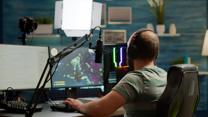 Excited streamer with headphones winning important online esport competition of space shooter playing on powerful computer. Professional pro gamer streaming videogames using professional microphone © DC Studio