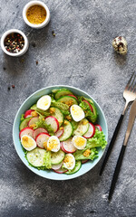 Vegetable, fresh salad with radish, egg and salad leaves in a blue plate on a concrete background.