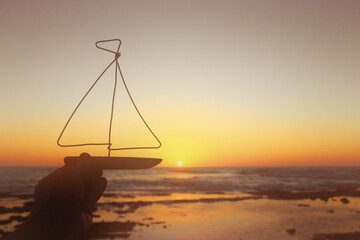 nautical concept with sail boat infront of sunset sea and beach landscape