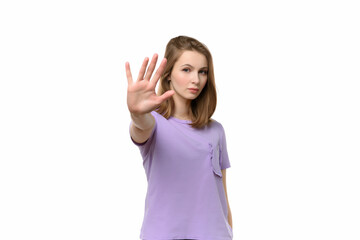 Fototapeta premium Portrait of a serious girl standing with outstretched hand showing stop gesture, refuse offer