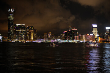 Night panorama of Hong Kong harbor and Kowloon side with illuminated skyscrapers and city lights reflecting on water